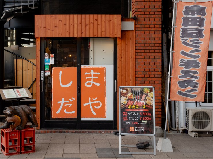 オレンジ色の「しまだや」看板が目印の店舗外観